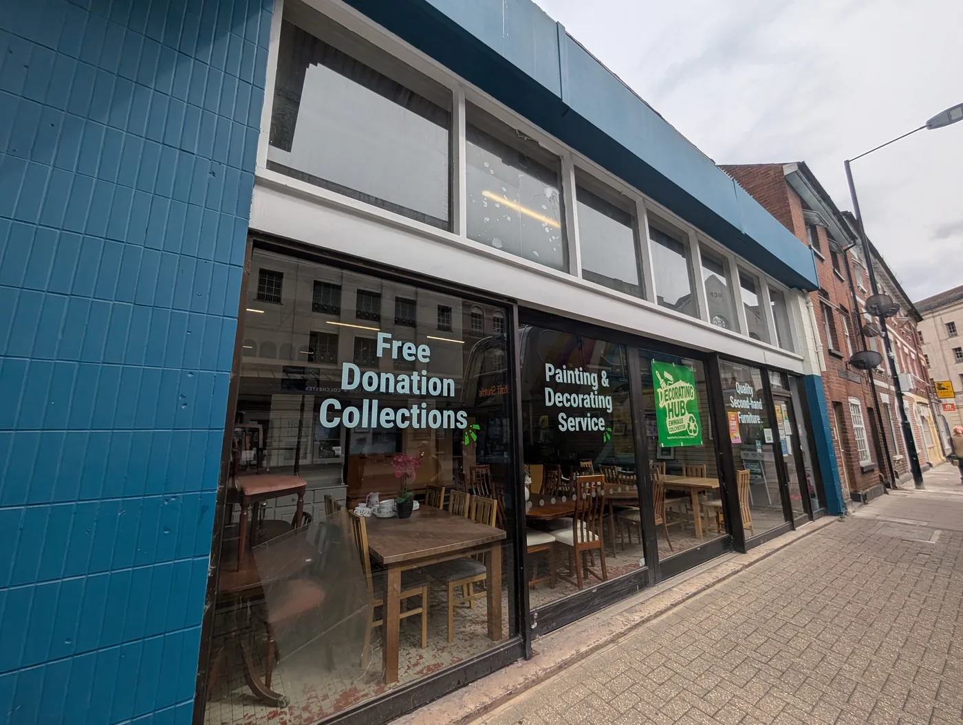 The Emmaus Works shopfront in Osborne Street, Colchester, with window lettering reading Free Donation Collections and Painting and Decorating Service